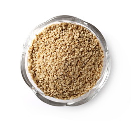 Organic integral sesame seeds in glass bowl isolated on white background, top view
