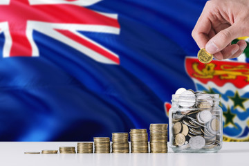 Business man holding coins putting in glass, Cayman Islands flag waving in the background. Finance...