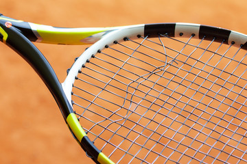Tennis racket with broken strings.