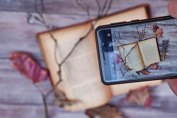 Book And Autumn Leaves Through Smartphone