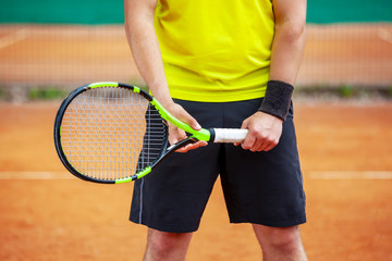 Midsection of male tennis player holding the racket.
