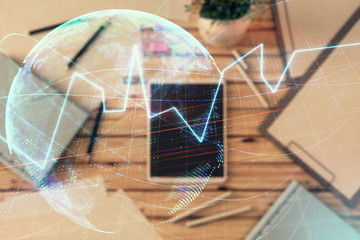 Double exposure of forex chart and world map on digital tablet laying on table background. Concept of market analysis