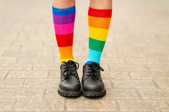 Female Legs In Lgbt Rainbow Socks Wearing Male Boots.