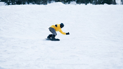 The guy is a snowboarder going down a hill crouching