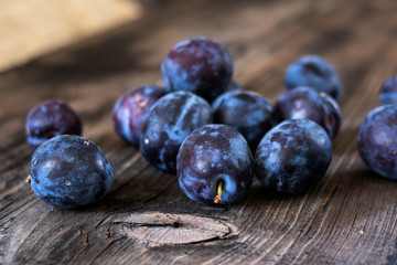 Fresh organic plums on old wooden table.
