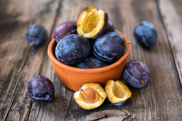 Fresh organic plums on old wooden table.