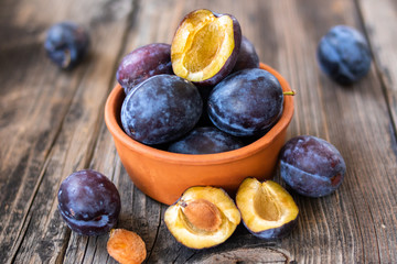 Fresh organic plums on old wooden table.