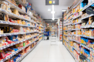 Abstract blurred supermarket aisle with colorful shelves and unrecognizable customers as background