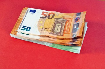 pile of euro banknotes, finance currency isolated on coral pink background. banknotes 100 and 50 euros. Several hundred euro banknotes. euro money cash, Concept of wealth, saving or spending money. 
