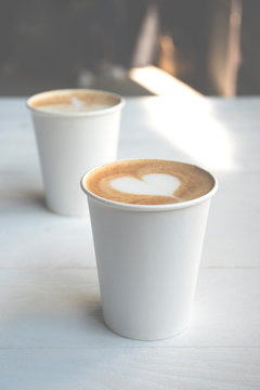 Two White Paper Cups Of Coffee On Wooden Table.