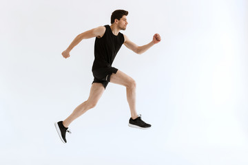 Concentrated young strong sports man running isolated over white wall background.
