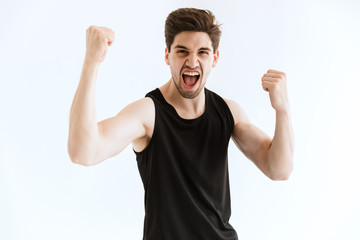 Strong young sports man running isolated over white wall background make winner gesture.