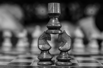 Black and white photo of two knights holding a rook