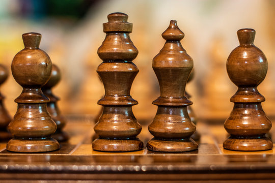 Chess pieces on board. King and Queen surrounded by bishops symbolizing royalty