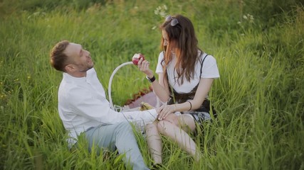 Loving couple sitting on grass in Park and eating apples.