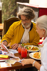 Concentrated man looking with his wife at photographs.