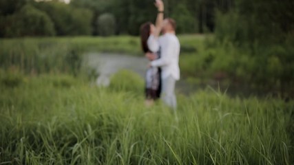 Couple in a park by the river in summer at sunset.