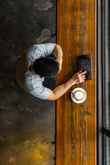 Asian young man using tablet while having hot cappuccino