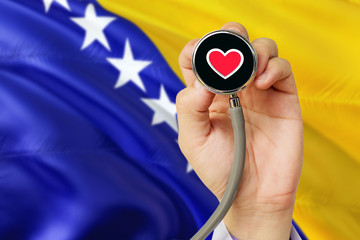 Doctor holding stethoscope with red love heart. National Bosnia Herzegovina flag background....