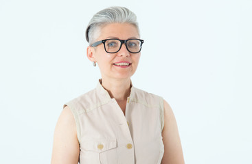 Portrait of a beautiful mature woman in glasses on a light background.