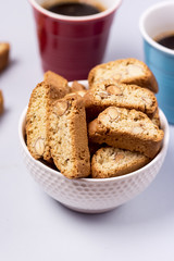Italian Almond Biscuit Biscotti or Cantuccini in a White Bowl Tasty Italian Dessert and Two Cup Of Coffee Blue Background Vertical