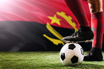 Close up legs of Angola football team player in red socks, shoes on soccer ball at the free kick or...