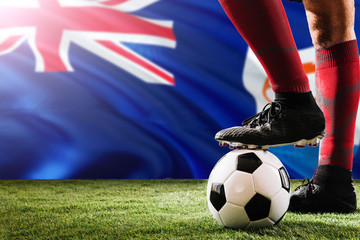 Close up legs of Anguilla football team player in red socks, shoes on soccer ball at the free kick or penalty spot playing on grass.