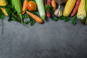 Assorted fresh vegetables on a black background. Corn, tomatoes, zucchini, carrot, beetroot, garlic, bean. Food concept. Flat lay, top view, copy space