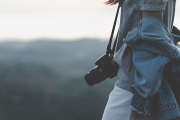 Close up portrait Asian woman photographer with jean jacket and camera at mountain peak in morning...