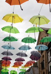 Fototapeta na wymiar Wales, the historic town city of Caernarfon. Inside the walled town, jolly, coloured umbrellas are placed above a narrow, old shopping street, giving the surroundings a touch of humour.