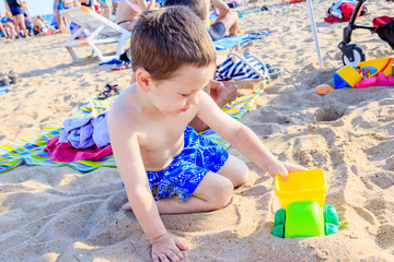 A boy plays a typewriter on the beach. Children's games. Beach in the summer. Small child
