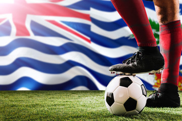 Close up legs of British Indian Ocean Territory football team player in red socks, shoes on soccer ball at the free kick or penalty spot playing on grass.
