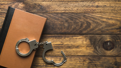 Top view book and handcuffs on wooden table