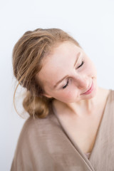 Fototapeta premium Attractive, beautiful young girl with brown hair on a white background. The concept of student life, youth.