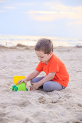 A boy plays a typewriter on the beach. Children's games. Beach in the summer. Small child