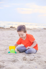 A boy plays a typewriter on the beach. Children's games. Beach in the summer. Small child