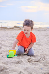 A boy plays a typewriter on the beach. Children's games. Beach in the summer. Small child