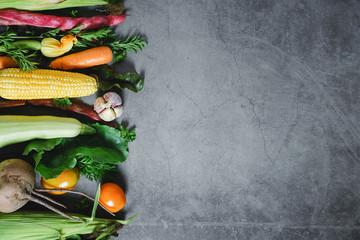 Healthy food clean eating selection. Corn, tomatoes, zucchini, carrot, beetroot, garlic, bean on a black background. Food concept. Flat lay, top view. Free space for your text.