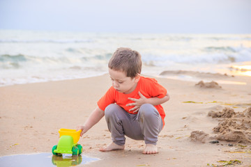 A boy plays a typewriter on the beach. Children's games. Beach in the summer. Small child