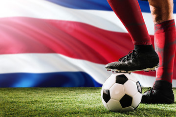 Close up legs of Costa Rica football team player in red socks, shoes on soccer ball at the free...