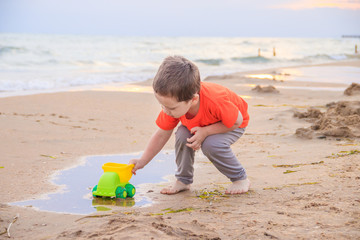 A boy plays a typewriter on the beach. Children's games. Beach in the summer. Small child