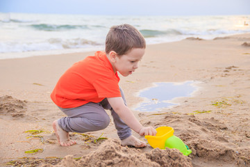 A boy plays a typewriter on the beach. Children's games. Beach in the summer. Small child
