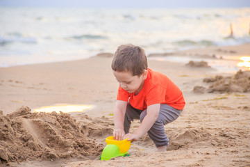 A boy plays a typewriter on the beach. Children's games. Beach in the summer. Small child