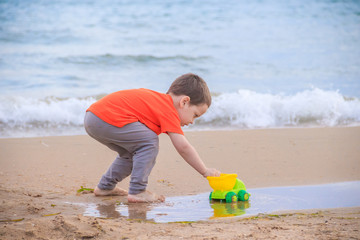 A boy plays a typewriter on the beach. Children's games. Beach in the summer. Small child