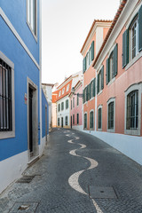 Narrow cobblestone alley between colourful stone houses in Cascais, Portugal