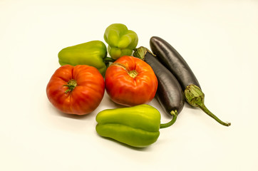 A group of fresh vegetables from green sweet peppers and  large red tomatoes and black- purple eggplants grown in Armenia lies on a white background