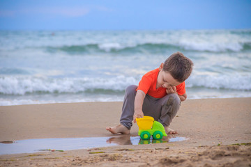 A boy plays a typewriter on the beach. Children's games. Beach in the summer. Small child