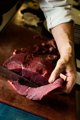 man cutting a piece of beef in a professional kitchen