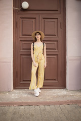 Fashionable young woman in a yellow suit stands near the door. Urban setting