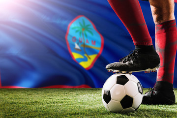 Plakat Close up legs of Guam football team player in red socks, shoes on soccer ball at the free kick or penalty spot playing on grass.